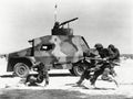 Soldiers running along side of tank in the desert