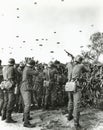 Soldiers shooting at enemy parachuting into field Royalty Free Stock Photo