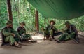 Soldiers sitting under a canopy.