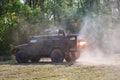 Soldiers of special purpose detachment driving in an armoured car across the field and shooting a machine gun