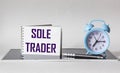 SOLE TRADER, text on white notepad on black and white background with clock and pen Royalty Free Stock Photo
