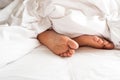 Sole of woman foot in messy blanket on bed. White pillow with bl Royalty Free Stock Photo