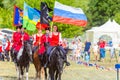 Solemn entry of a group of horse racing with flags in the meadow of the festival