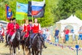 Solemn entry of a group of horse racing with flags in the meadow of the festival