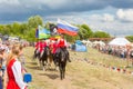 Solemn entry of a group of horse racing with flags in the meadow of the festival