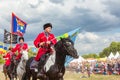 Solemn entry of a group of horse racing with flags in the meadow of the festival