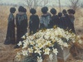A solemn group of mourning African American women stand together in a picturesque field, sharing stories and memories of