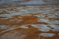 Solfatare mudpot s in the geothermal area Hverir, Iceland. The area around the boiling mud is multicolored and cracked