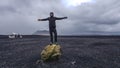 Iceland - Young man standing on a big rock with a plane wreck in the back