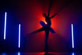 Solhouette of ballerina is practicing elements in studio with neon colorful light. Young woman dancing in classic tutu