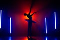 Solhouette of ballerina is practicing elements in studio with neon colorful light. Young woman dancing in classic tutu