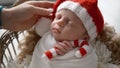 Solicitous Mother Softly Stroking Her Newborn Baby Boy In Santa Hat