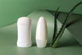 Solid antiperspirant, roll on deodorant and two fresh aloe leaves over wavy green background. Natural herbal cosmetics for skin