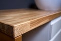 Solid ash glued timber corner table top closeup. Bathroom interior contemporary design countertop tabletop with sink.