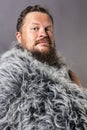 Solid bearded man in a fur mantle studio portrait