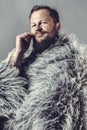 Solid bearded man in a fur mantle studio portrait Royalty Free Stock Photo