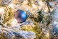 A solid blue Christmas ornament on a flocked Christmas tree