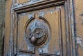 Solid brass heavy classic door knocker in the shape of an owl with green eyes on a weathered dark green painted door