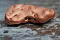 Solid copper nugget lying on wooden background, macro color photo Royalty Free Stock Photo