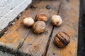Solid and embossed brown-shelled walnuts lie on a wooden table