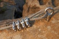 Solid knot on steel rope. Iron twisted rope fixed in block by screws snap hooks. Detail of rope end anchored into sandstone rock Royalty Free Stock Photo