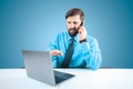 Solid man in the office at the computer talking on the phone and pointing at the laptop monitor with his hand Royalty Free Stock Photo