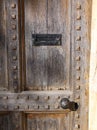 A heavey and huge old door with metal furnishings including antique doorknob and letter box