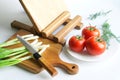 Solid oak kitchen cutting boards, knife, chopped green onion and fresh tomato on a white background. Concept of cooking a rustic Royalty Free Stock Photo