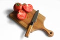 Solid oak wooden cutting board, chopped red tomato and sharp knife on a white background. The concept of preparing a summer salad Royalty Free Stock Photo