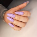 Solid purple gel polish on very long nails without design. Women`s hands with a lilac manicure. Royalty Free Stock Photo