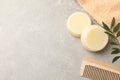 Solid shampoo bars, towel green twigs and comb on grey table, flat lay. Space for text