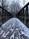 A SOLID WOODEN BRIDGE GUIDES HIKERS ALONG A SNOWY TRAIL IN A PUBLIC PARK