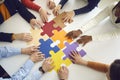 Office team assembling jigsaw puzzle pieces on table top view on hands Royalty Free Stock Photo