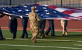 Solider in camouflage caring large American flag on field before a football game Royalty Free Stock Photo