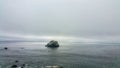 Solitary boulder against moody ocean sky. Stark foggy vanishing point. Background. Minimalism.