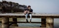 Solitary Boy Playing Guitar on the Pier