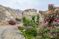 Solitary buddhist monastery in mountains with blooming rose shrubs Royalty Free Stock Photo