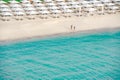 Lonely couple walking at the empty beach beside the turquoise clear water of Indian Ocean in Dubai. Royalty Free Stock Photo