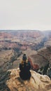 A solitary figure sits in contemplation on the edge of the Grand Canyon, gazing into the vast, colorful landscape spread