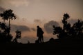 Solitary figure stands atop a hill, their silhouette illuminated by the setting sun