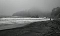 Solitary figure walking along a foggy beach at Muir Beach, California