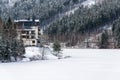 Solitary hotel building in a beautiful snowy winter landscape with forest and frozen dam