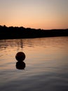 Sunset on pond with ball floating away