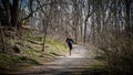 Solitary male runner jogging along a gravel pathway in a lovely wooded area in the St. Catharines, Ontario, Canada region. March