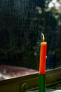 A solitary orange candle casts a warm glow on a windowsill