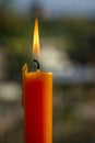 A solitary orange candle casts a warm glow in a window