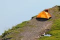 Solitary orange tent camped near water edge