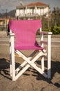 A solitary pink canvas chair sits abandoned on a serene Greek beach, bathed in the golden light of the setting sun, offering a