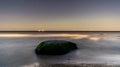 A solitary rock in a flat sea at night Royalty Free Stock Photo