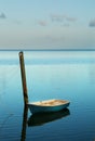 Solitary small boat moored at soft cyan blue sunrise.